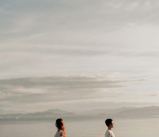 15 Signs You’re in a Karmic Relationship: What It Means Couple standing apart on a beach at sunset